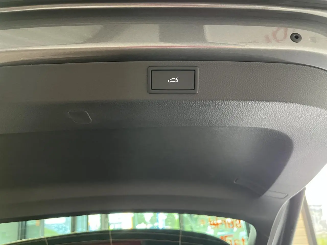 Bouton d'ouverture électrique du hayon du coffre sur un SUV SKODA KAROQ gris 2025, vue intérieure du hayon ouvert.