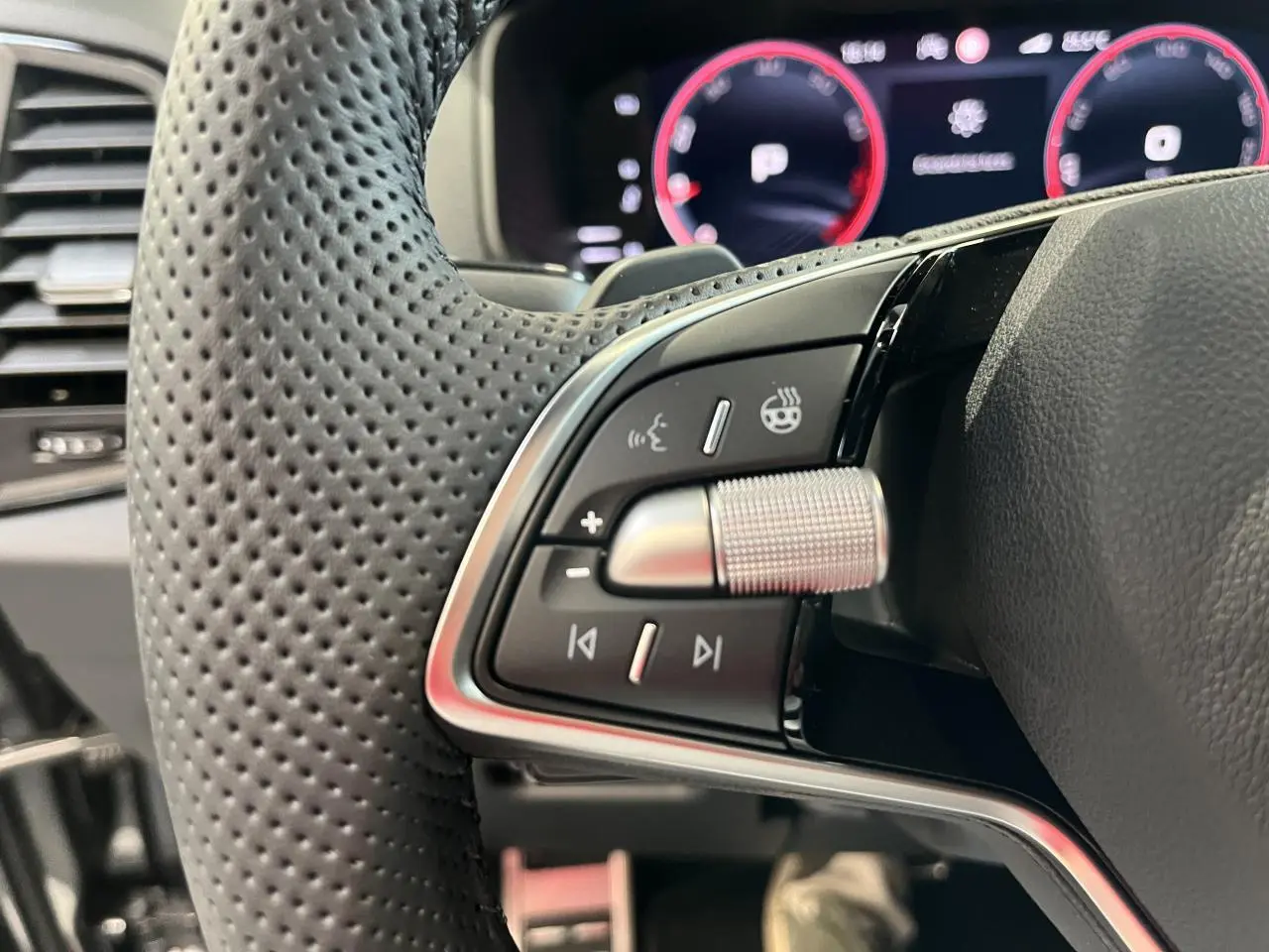 Gros plan sur la commande multifonction gauche du volant perforé noir du Skoda Karoq 2025 finition Sportline.