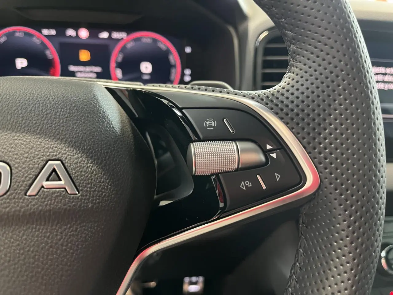 Gros plan sur les commandes à droite du volant cuir perforé du Skoda Karoq 2025, tableau de bord digital en arrière-plan.