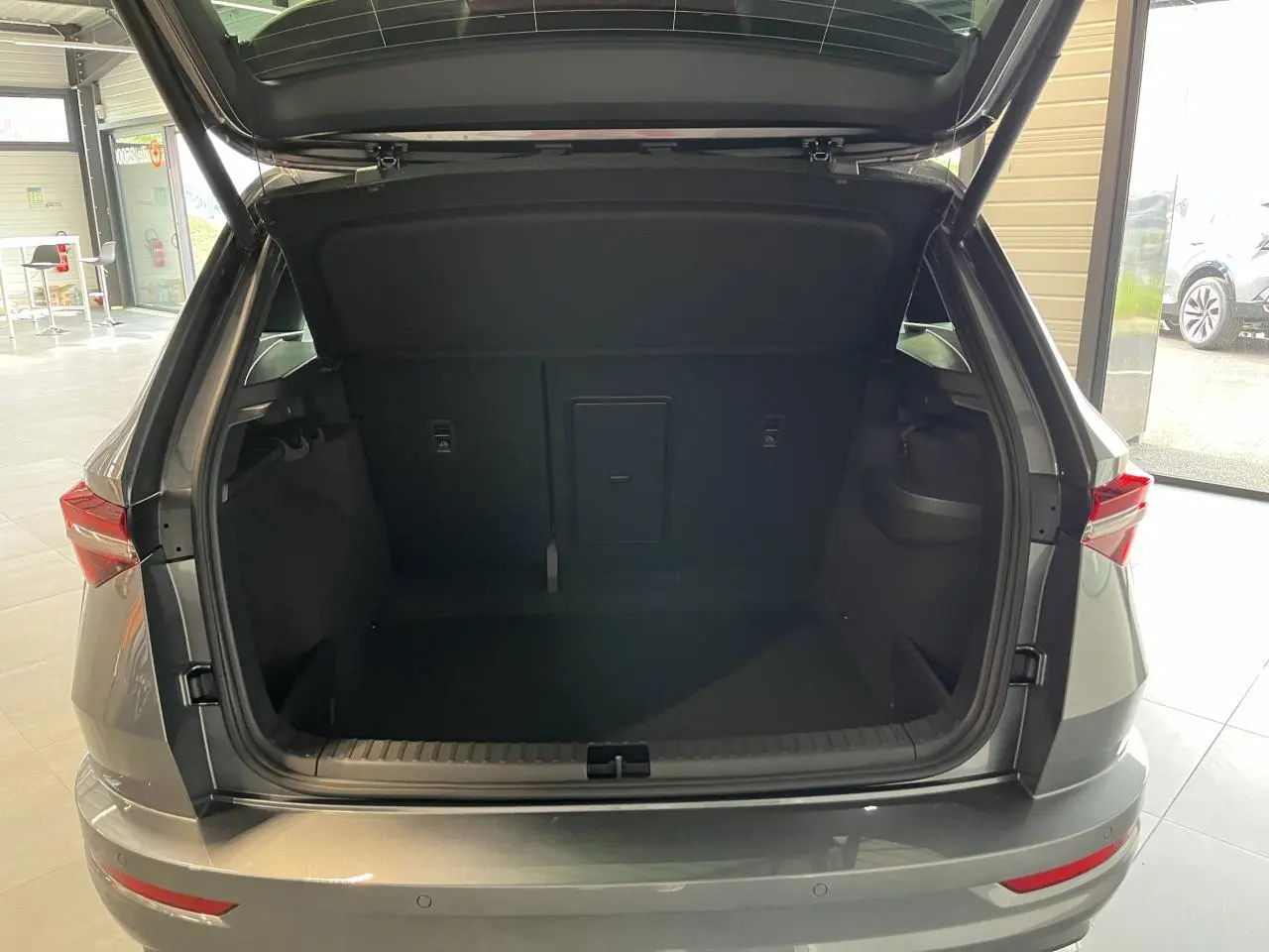 Coffre ouvert vu de l'arrière d'un SUV SKODA KAROQ gris avec hayon électrique dans un showroom.