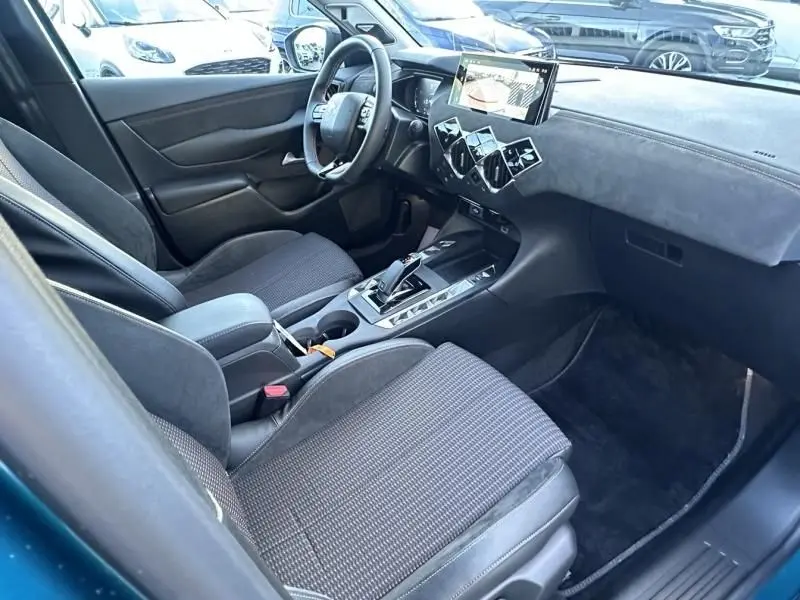 Intérieur avant droit du DS3 1.2 Hybride 145 Étoile 2025 bleu métal, avec tableau de bord moderne et écran tactile central.