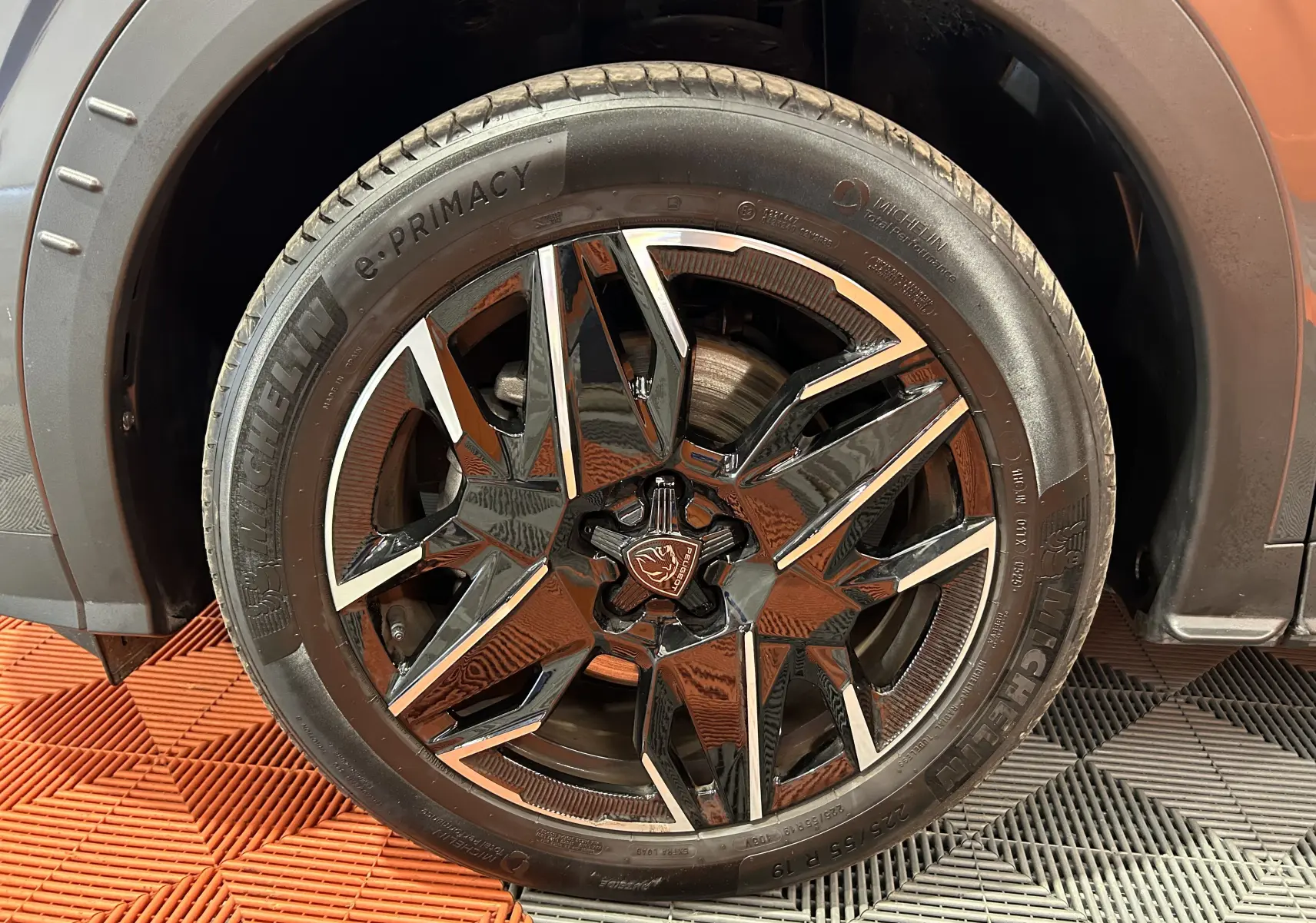 Gros plan sur la roue avant gauche du Peugeot 5008 gris titane, mettant en valeur la jante noire et argentée au design moderne.