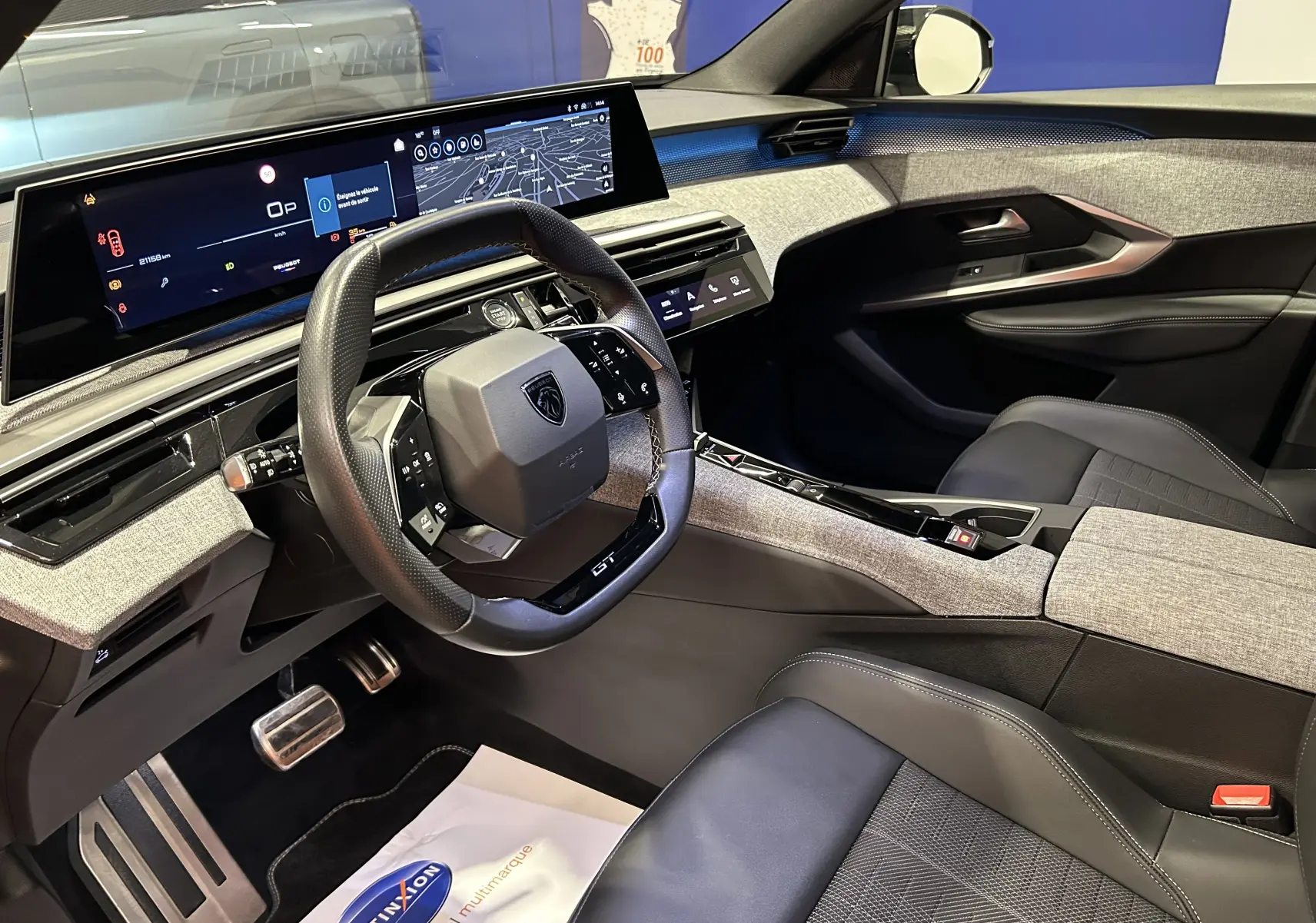 Vue intérieure côté conducteur du Peugeot 5008 III Hybrid 145 e-DCS6 GT, avec tableau de bord numérique et sellerie noire.
