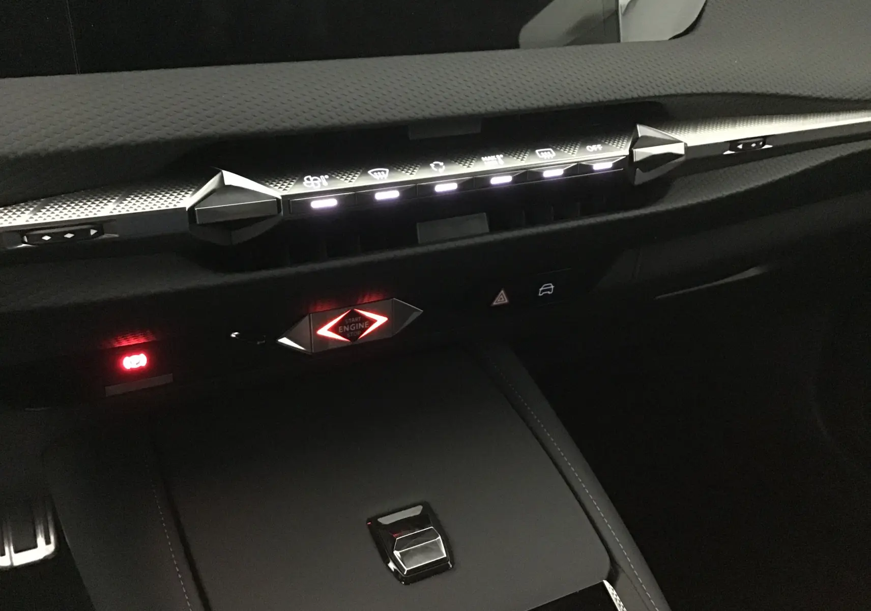 Vue rapprochée du tableau de bord noir du DS4 2022, mettant en valeur les commandes tactiles et le bouton start engine rouge lumineux.
