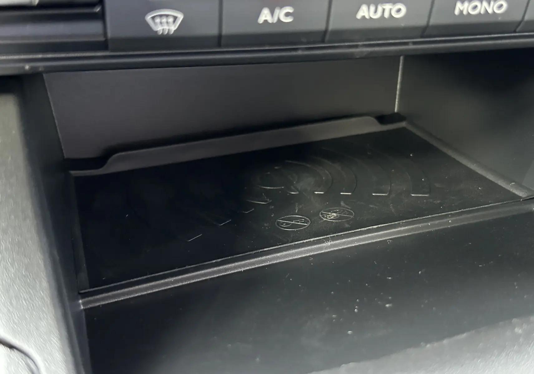 Détail du compartiment de recharge sans fil sous les commandes de climatisation du Peugeot Partner Fourgon blanc.