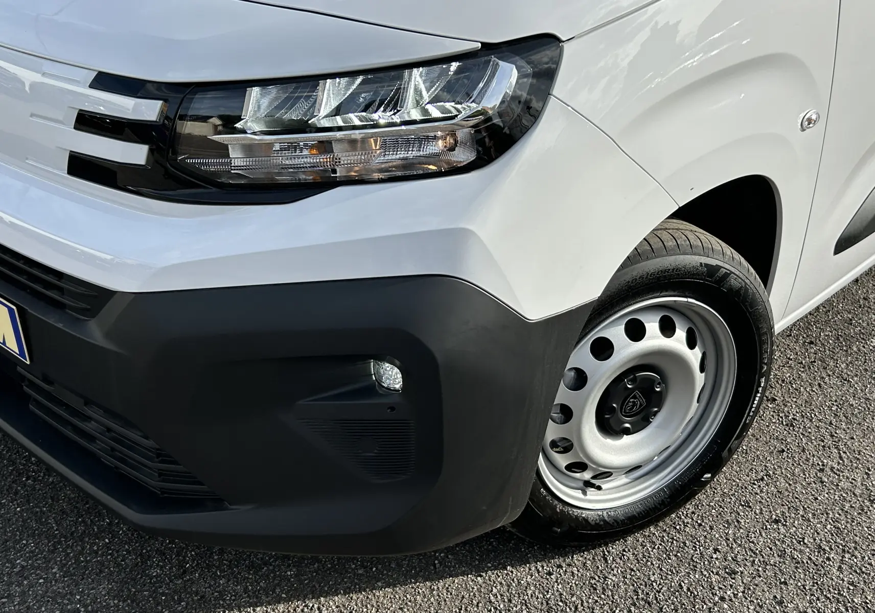 Gros plan sur l'avant droit blanc du Peugeot Partner Fourgon avec phare moderne et pare-chocs noir mat.