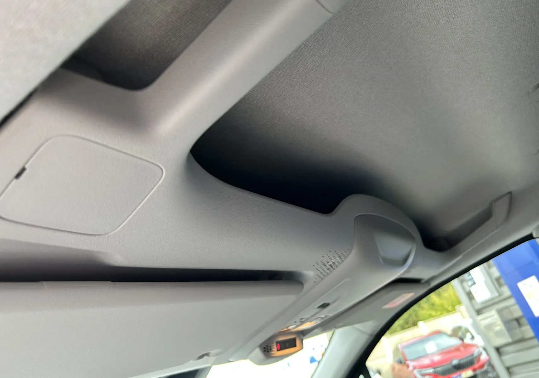 Détail du plafond intérieur gris clair du Peugeot Partner Fourgon avec pare-soleil baissé et vitre avant visible.