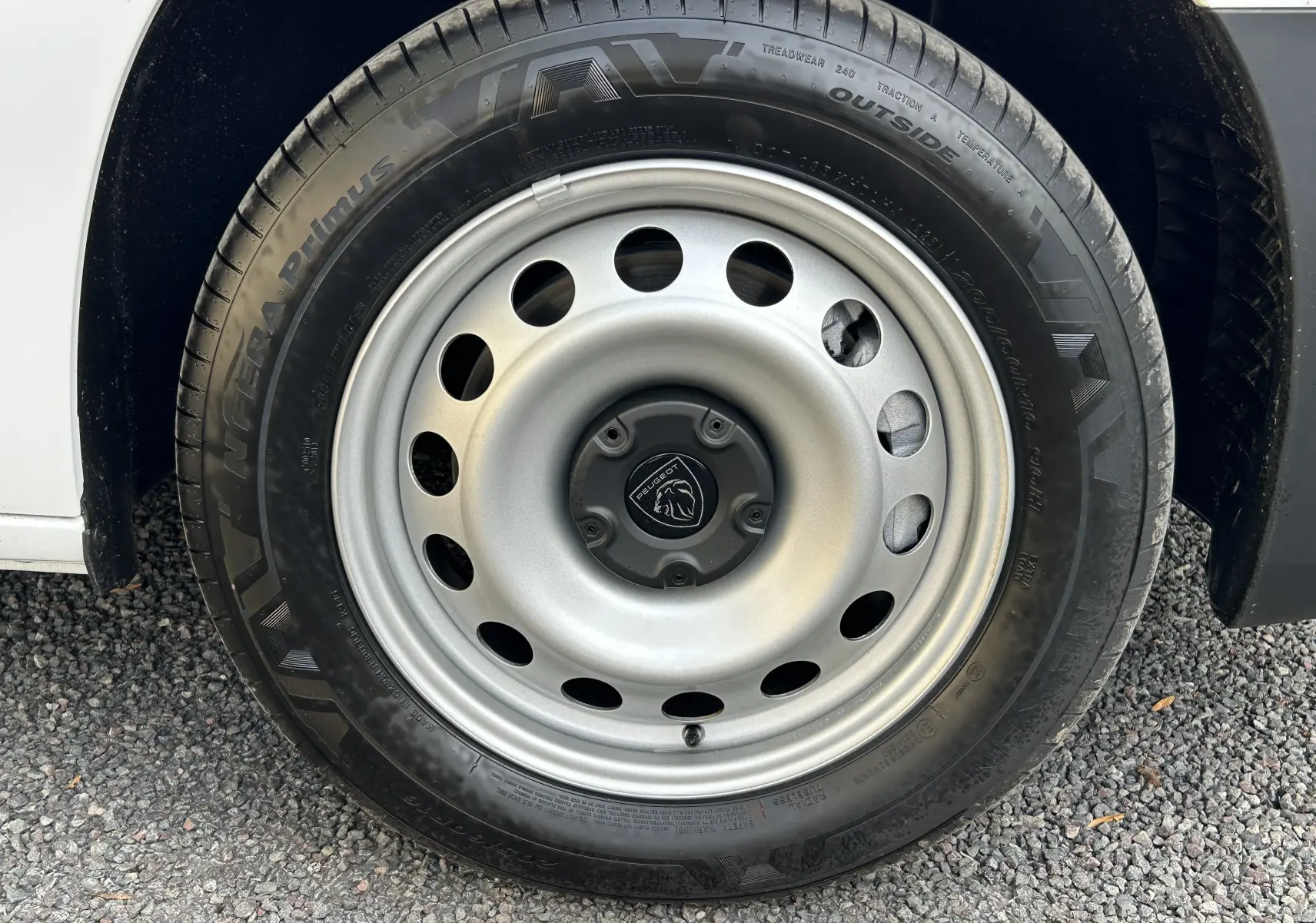 Gros plan sur la roue acier grise du Peugeot Partner Fourgon blanc, avec logo lion au centre du moyeu.