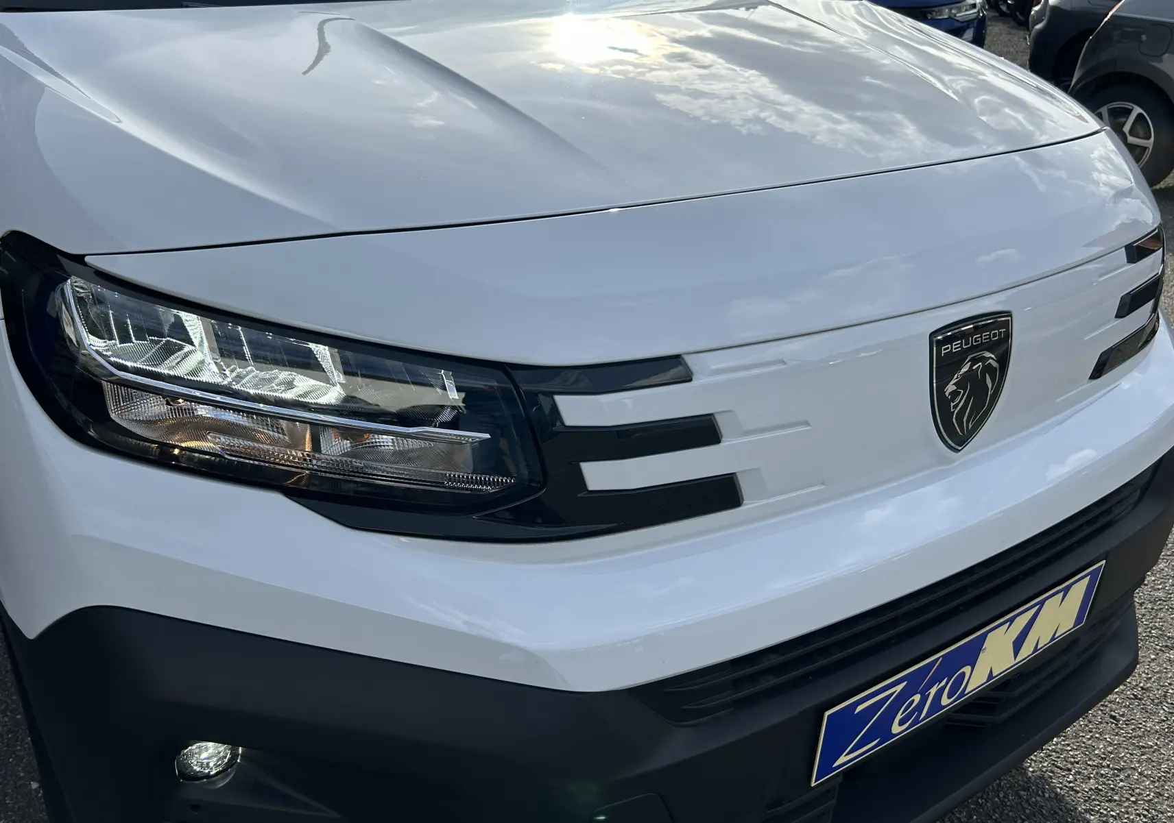 Gros plan sur l'avant blanc du Peugeot Partner Fourgon 2025 avec phares LED et calandre noire distinctive.