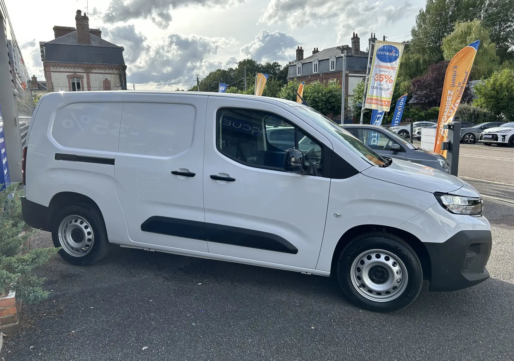 Vue de profil côté droit d'un Peugeot Partner Fourgon blanc avec poignées et rétroviseurs noirs sur parking extérieur.