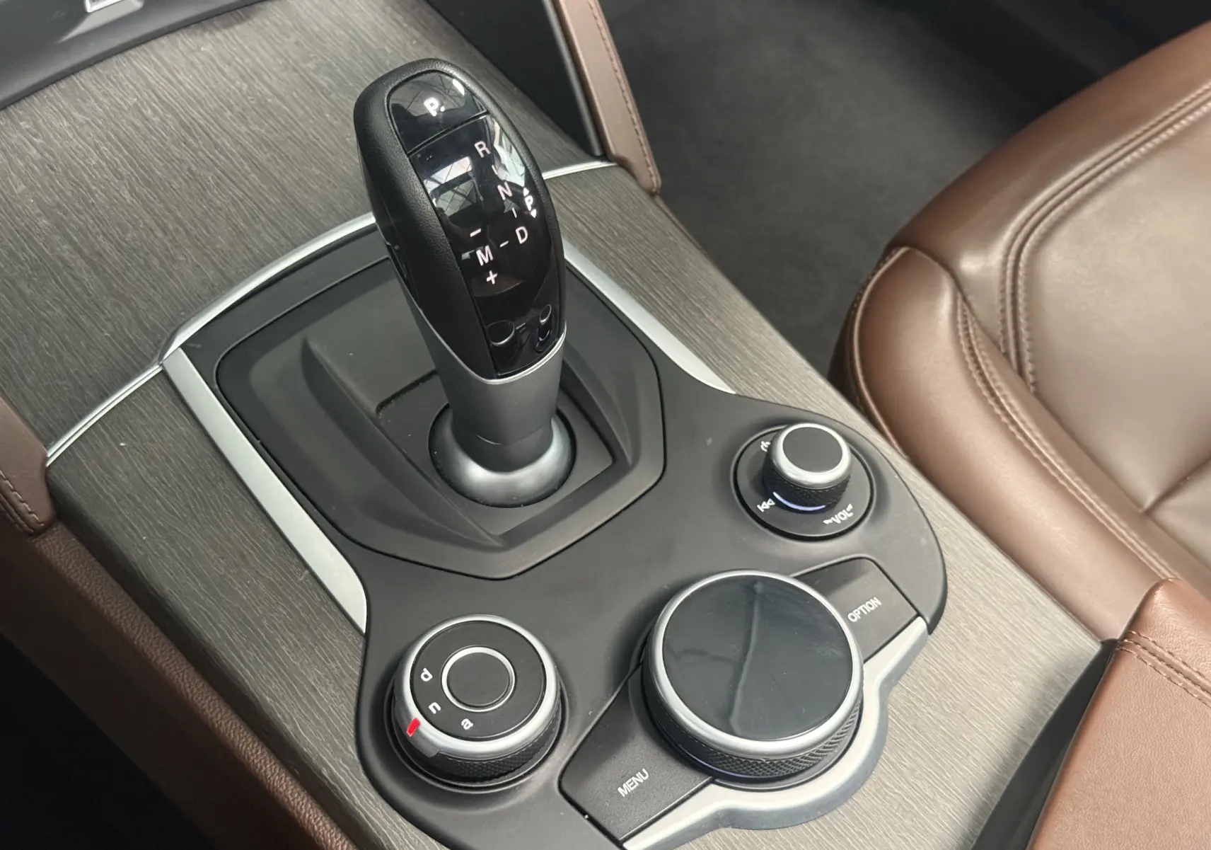 Gros plan sur la console centrale grise avec levier de vitesses automatique et commandes circulaires dans l'Alfa Romeo Stelvio Lusso 2017.