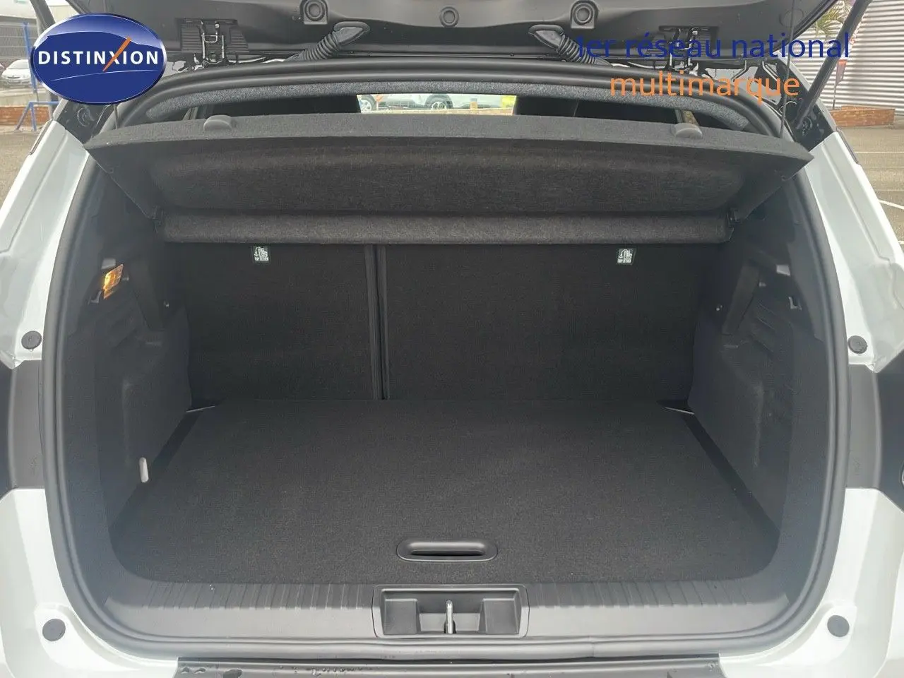 Coffre ouvert vu de l'arrière d'un Renault Captur blanc nacré au toit noir, montrant un espace de chargement propre et spacieux.