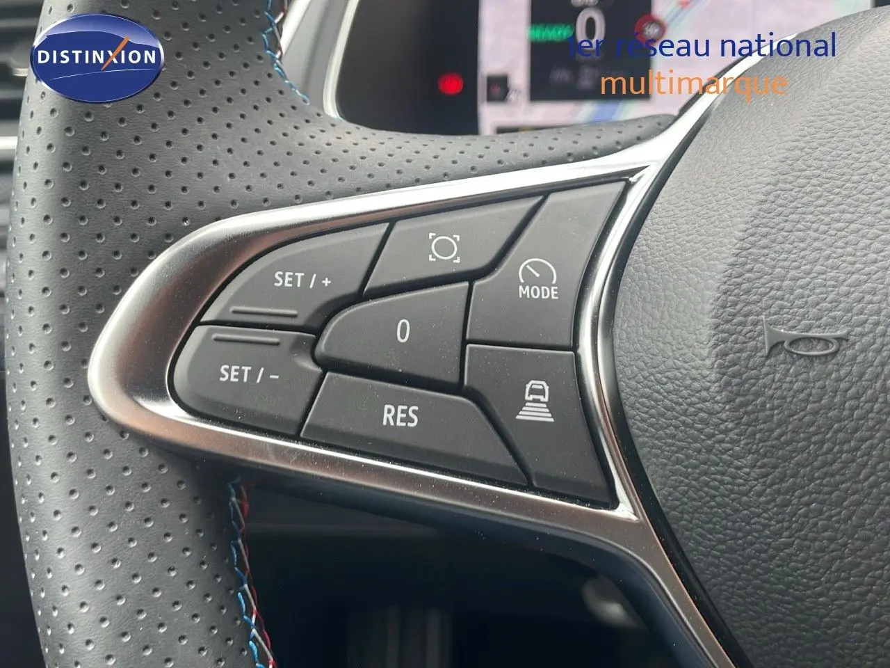 Gros plan sur les commandes au volant en cuir perforé noir du Renault Captur E-Tech hybride blanc nacré toit noir.