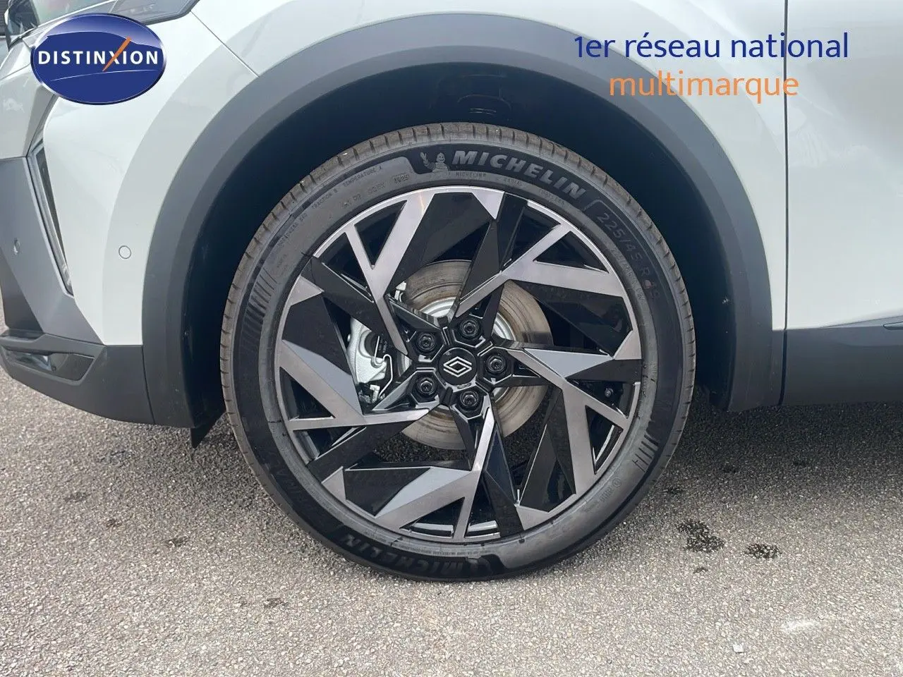 Gros plan sur la roue avant gauche du Renault Captur blanc nacré avec jante noire et argentée au design géométrique.