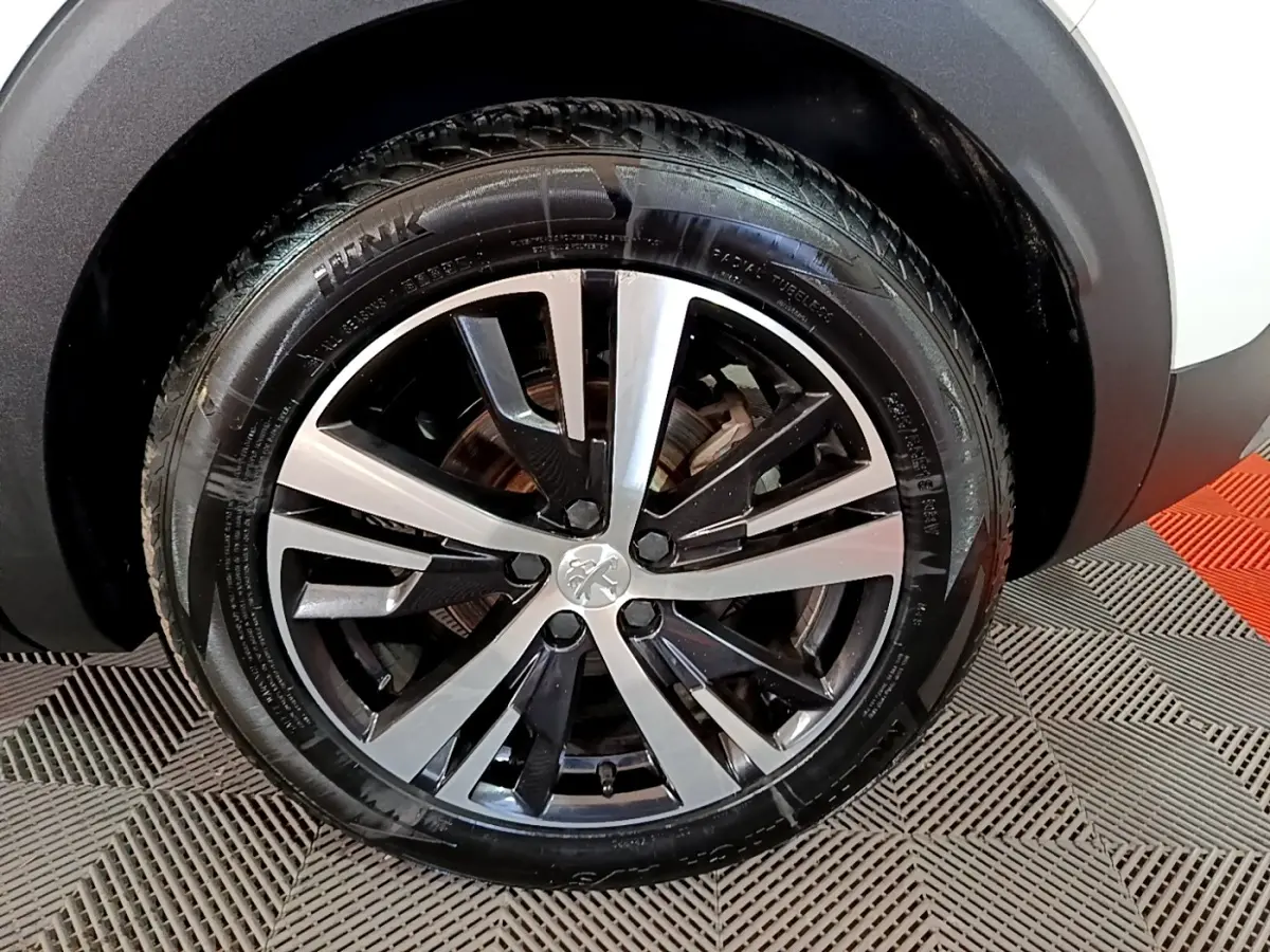 Gros plan sur la jante alliage bicolore noire et argentée du Peugeot 3008 blanc, roue avant droite visible.