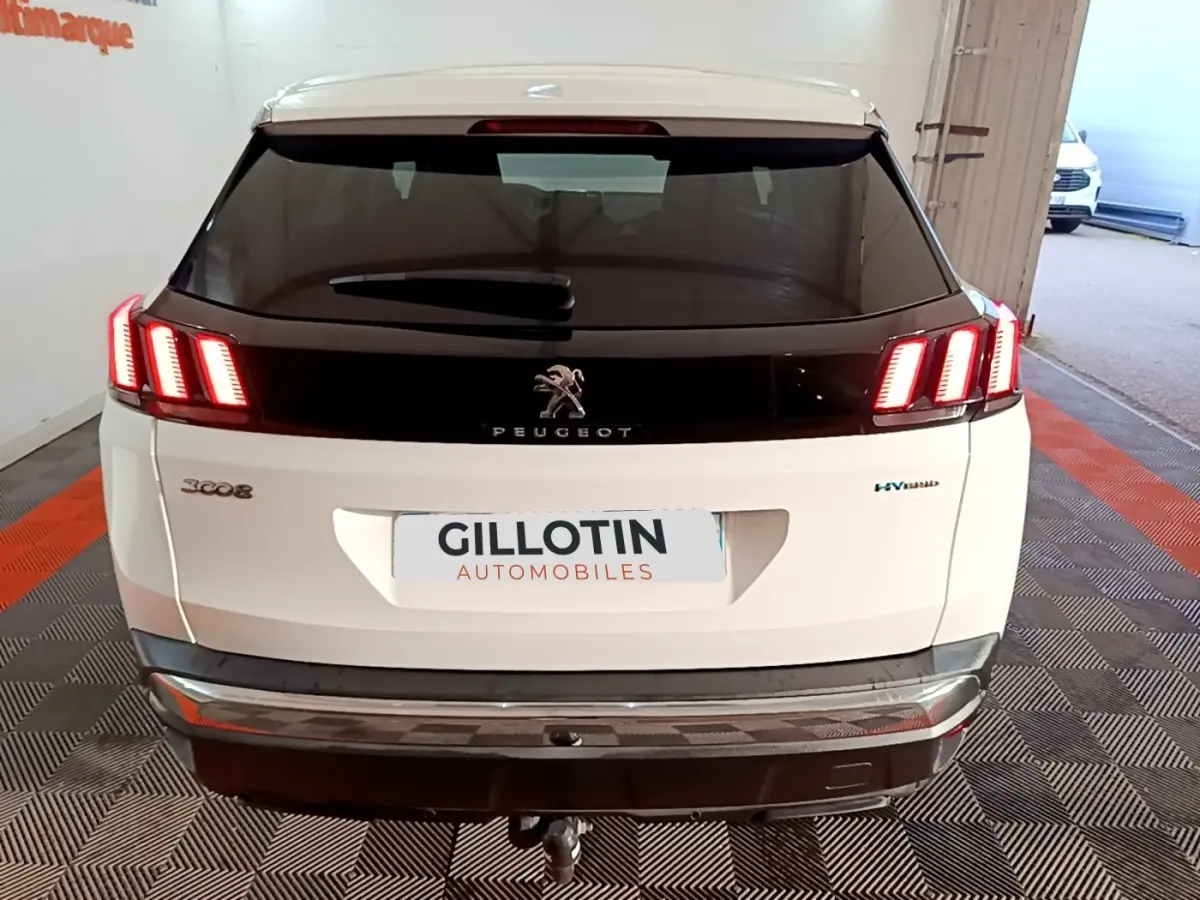 Vue arrière d'un Peugeot 3008 blanc hybride rechargeable avec feux LED allumés et logo central noir brillant.