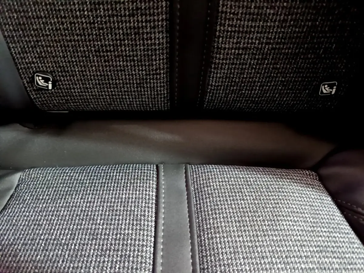 Gros plan sur la banquette arrière en tissu gris à motifs avec fixation Isofix visible sur un Peugeot 3008 blanc.
