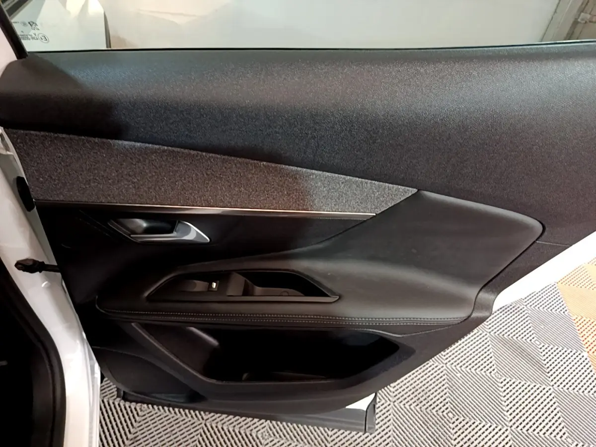 Vue intérieure de la porte côté gauche du Peugeot 3008 blanc, avec garniture noire et commandes électriques.
