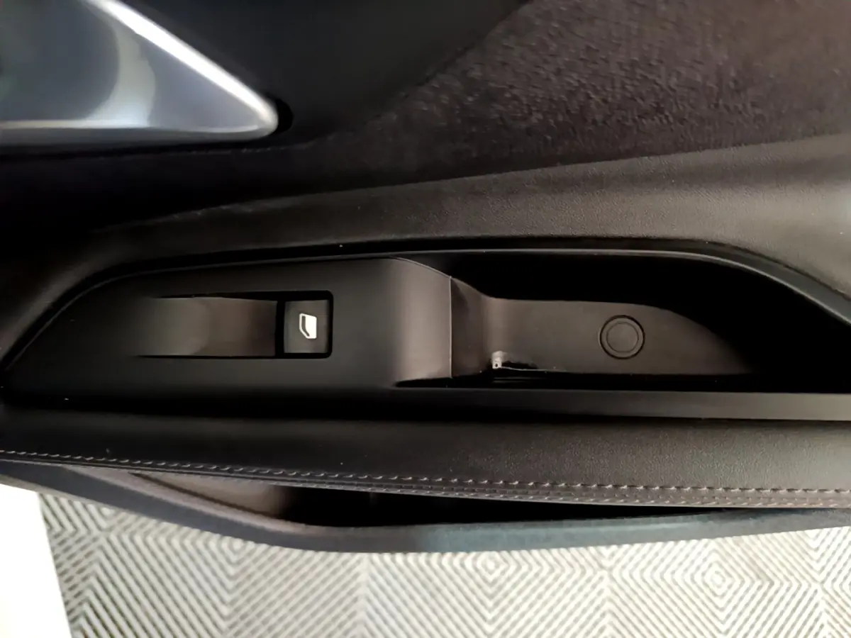Gros plan sur la commande de lève-vitre côté gauche intérieur d’un Peugeot 3008 blanc hybride rechargeable.