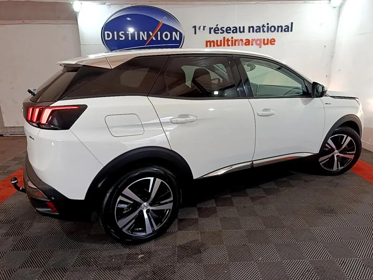 Peugeot 3008 hybride rechargeable blanc vue côté droit en intérieur avec feux arrière LED allumés et jantes alliage.