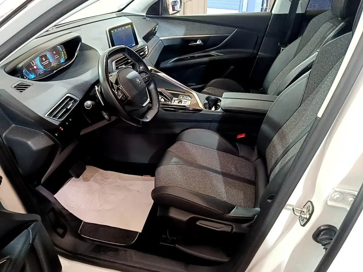 Vue intérieure côté conducteur du Peugeot 3008 blanc 2020, avec tableau de bord digital et sièges tissu-cuir gris.