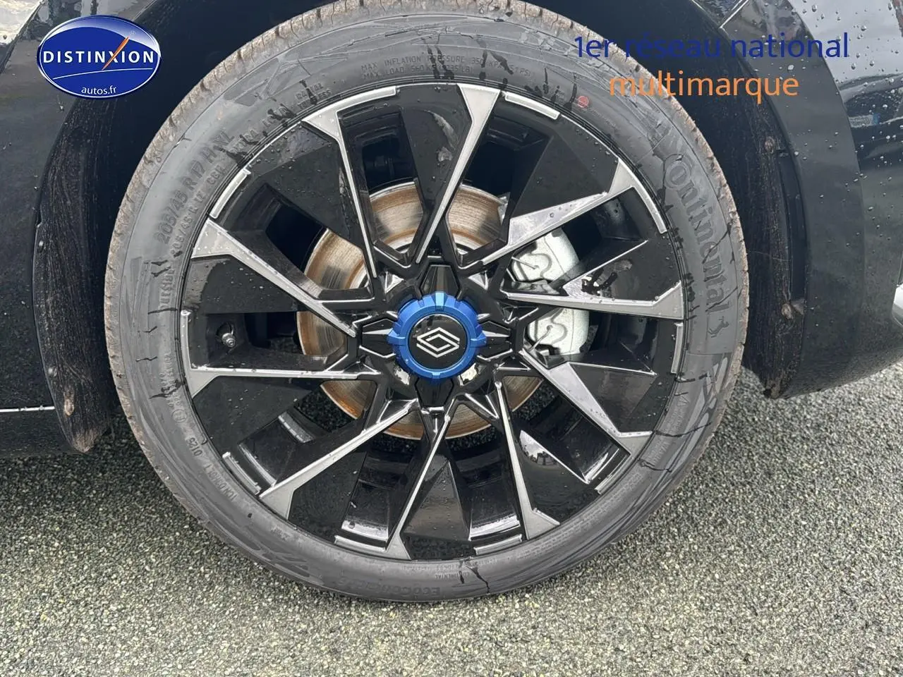 Gros plan sur la jante alu 17 pouces esprit alpine noire et argentée avec capuchon bleu d'une Renault Clio V noir étoile.