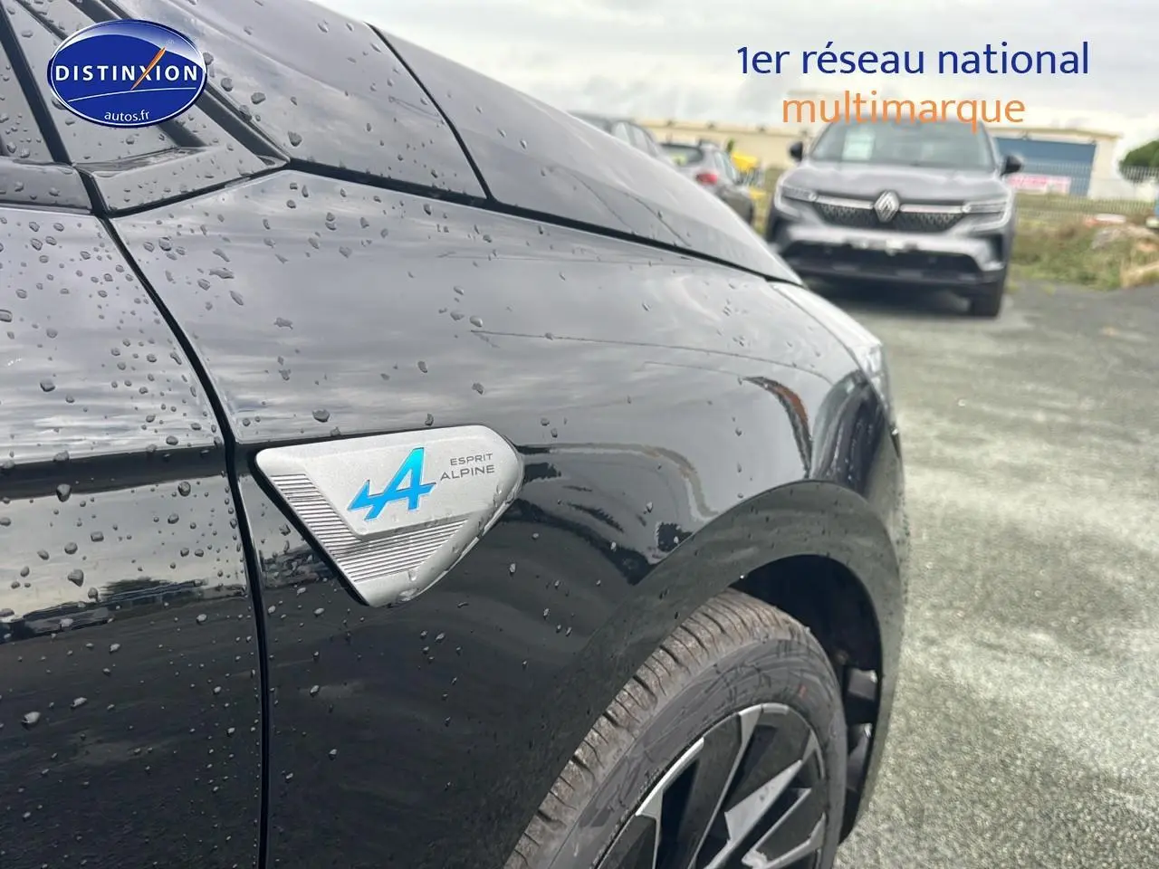 Gros plan sur l'aile avant gauche noire étoile d'une Renault Clio V esprit Alpine avec logo bleu distinctif.