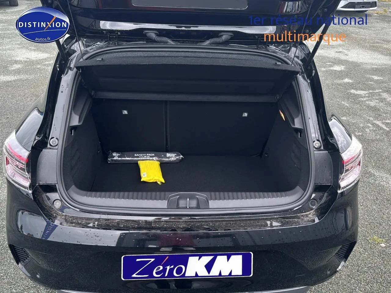 Coffre ouvert vu de l'arrière d'une Renault Clio V noire étoile avec intérieur de coffre vide et objets de sécurité.