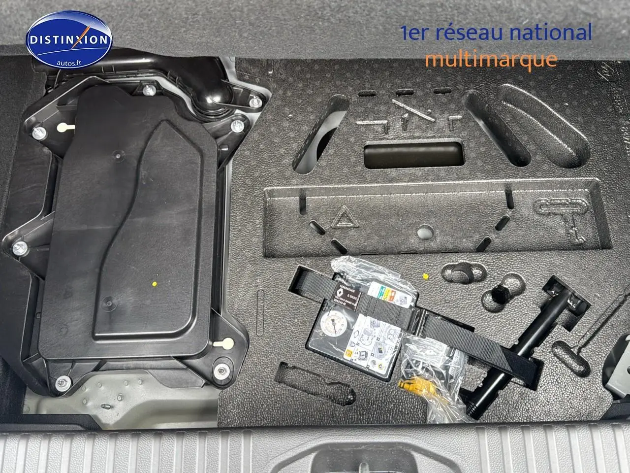 Gros plan sur le compartiment de rangement sous le coffre de la Renault Clio V noire étoile avec kit de réparation pneus.