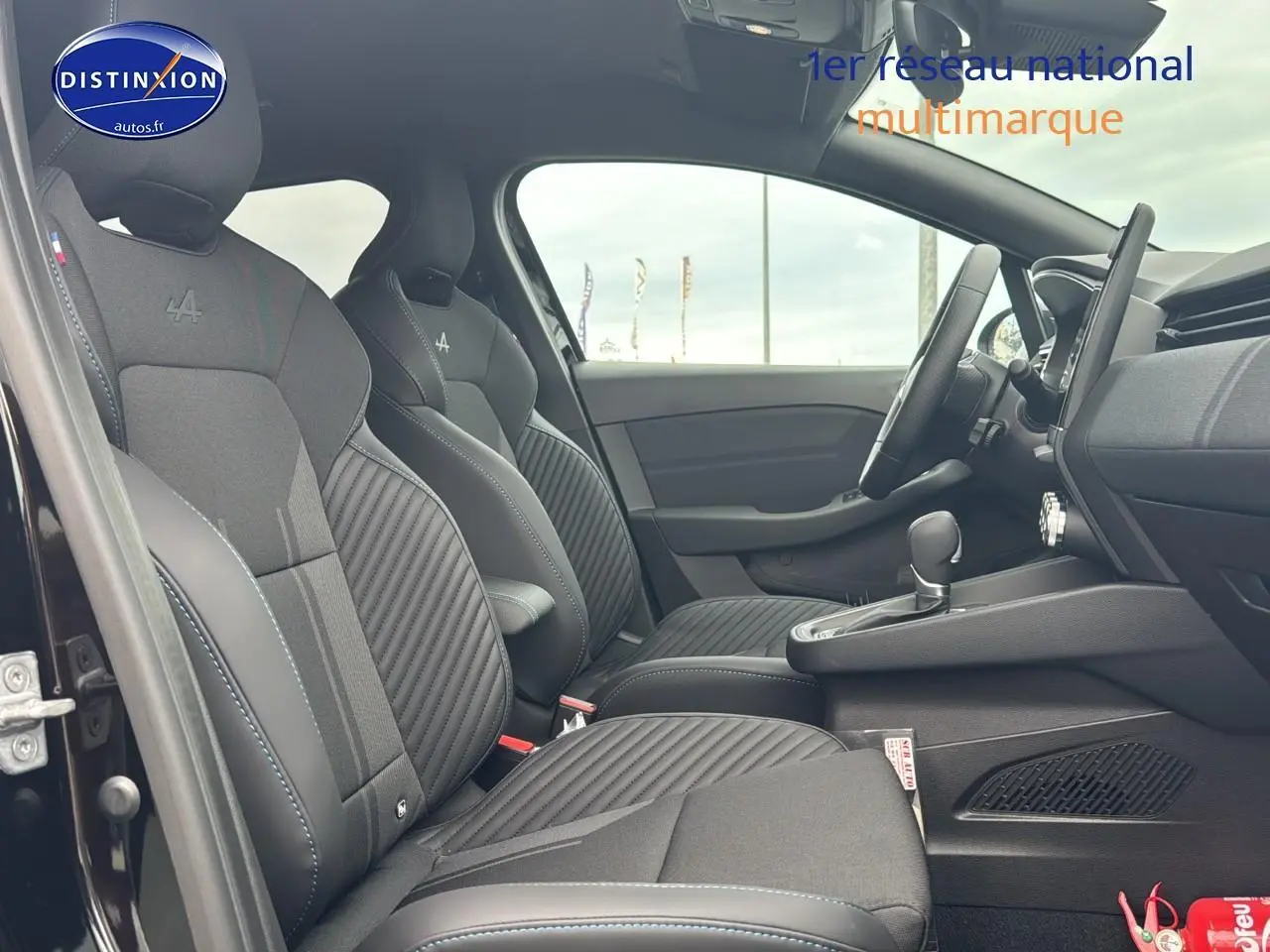 Intérieur côté gauche de la Renault Clio V hybride noir étoile, sièges sport esprit Alpine avec surpiqûres bleues.