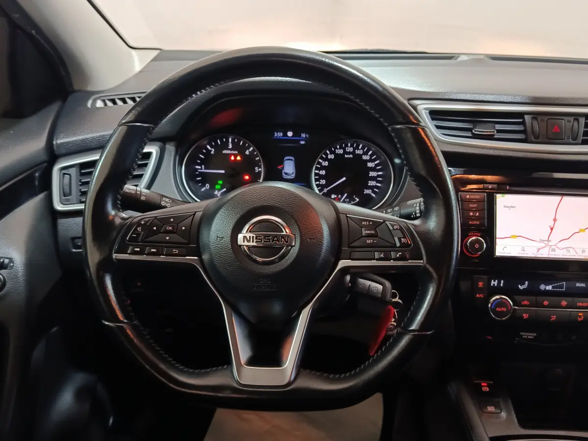 Vue rapprochée du volant en cuir noir et du tableau de bord avec écran tactile de navigation du Nissan Qashqai gris clair 2019.