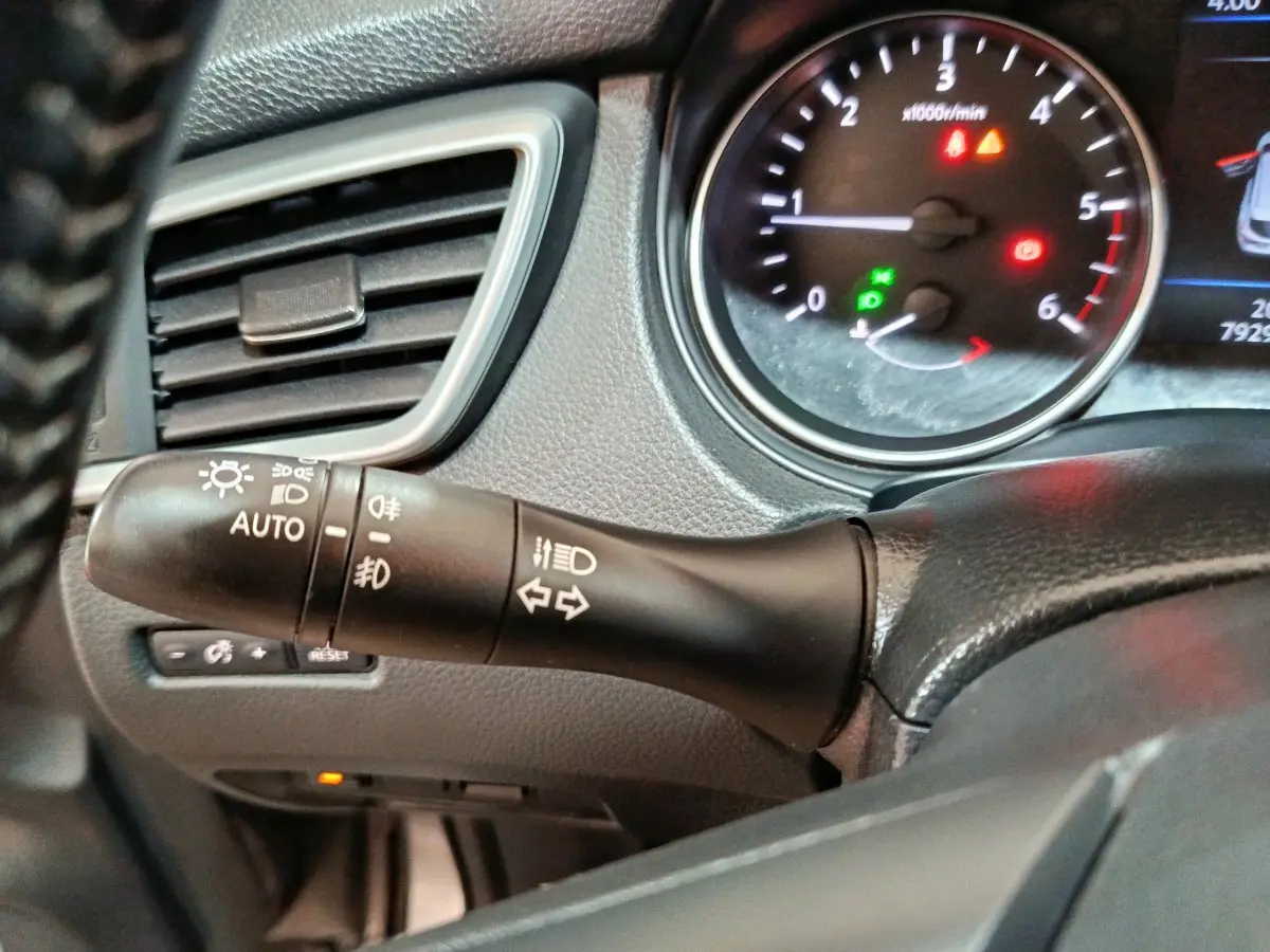 Gros plan sur la commande des phares et clignotants à gauche du volant dans le tableau de bord du Nissan Qashqai gris clair 2019.