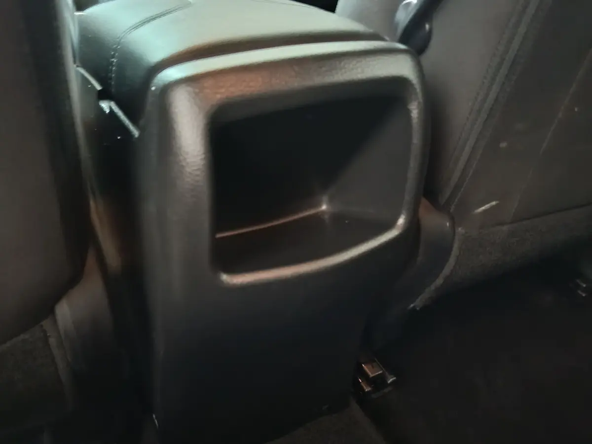 Rangement central arrière en plastique noir dans l'habitacle du Nissan Qashqai 1.5 DCI 115 Business Edition gris clair.