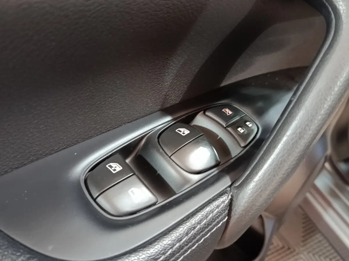 Gros plan sur les commandes des vitres électriques côté conducteur dans l'habitacle noir du Nissan Qashqai gris clair 2019.