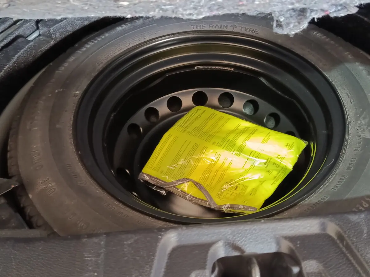 Gros plan sur la roue de secours galette noire du Nissan Qashqai 1.5 DCI 115 Business Edition 2019, sous le coffre.