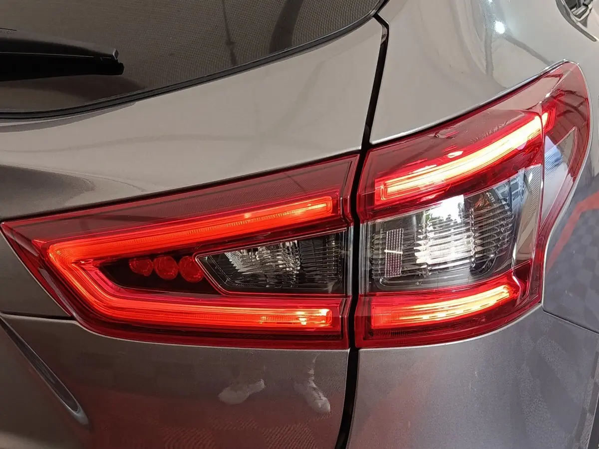 Gros plan sur le feu arrière droit rouge et blanc d’un Nissan Qashqai gris clair 2019.