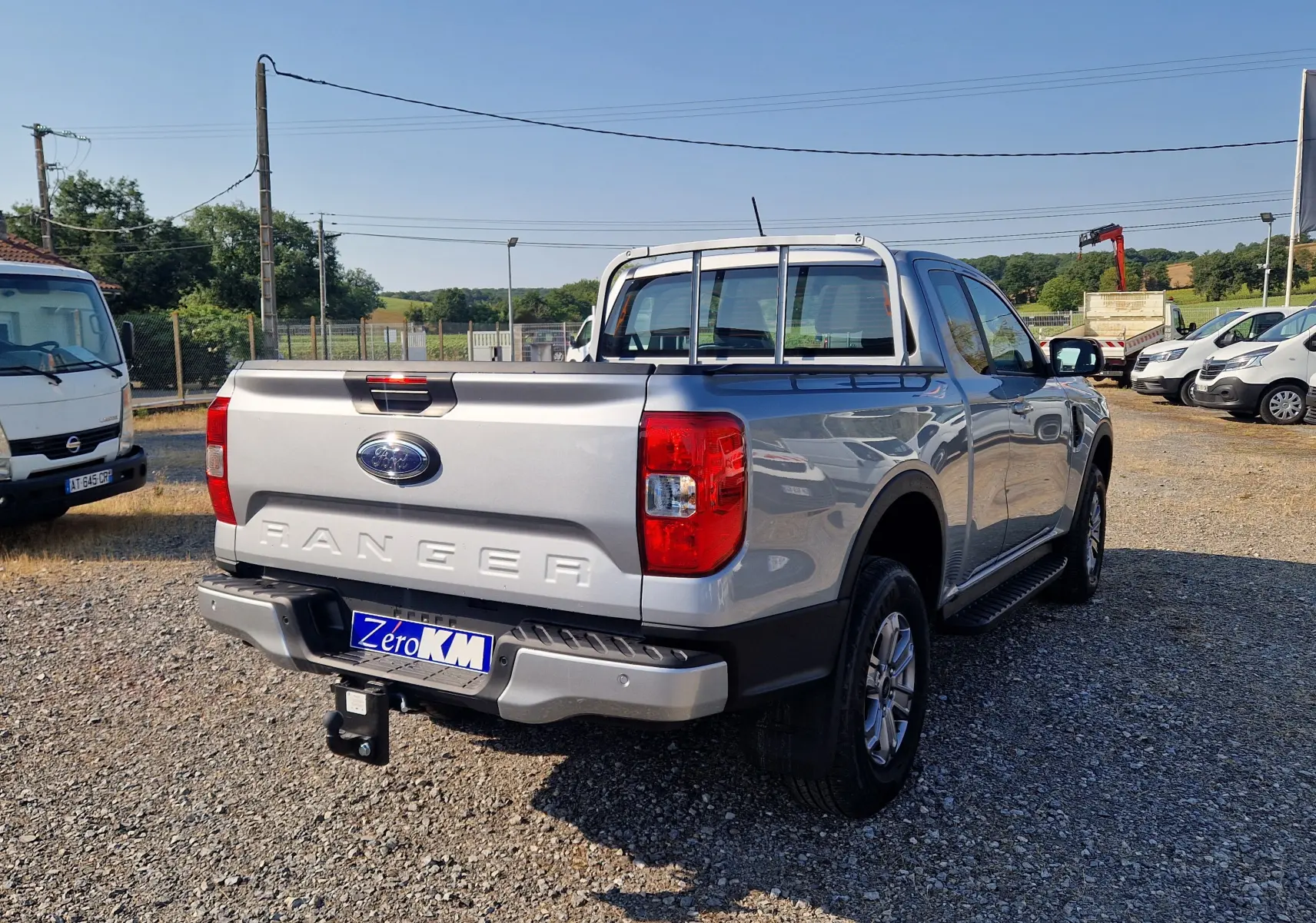 Ford Ranger Super Cabine gris Iconic vu en 3/4 arrière droit, avec attelage et barres de protection sur la benne.