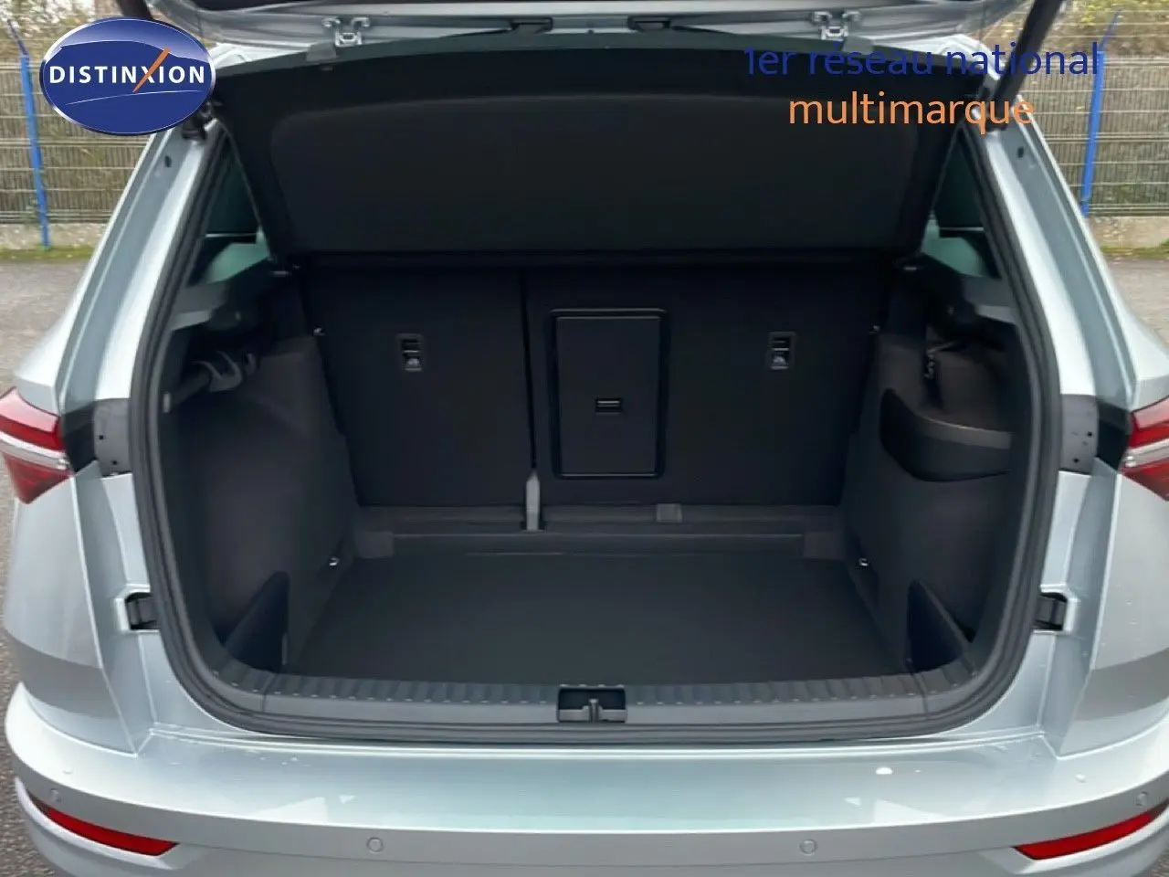 Coffre ouvert d’un Skoda Karoq gris argent métal vu de l’arrière, montrant un espace de chargement spacieux et propre.