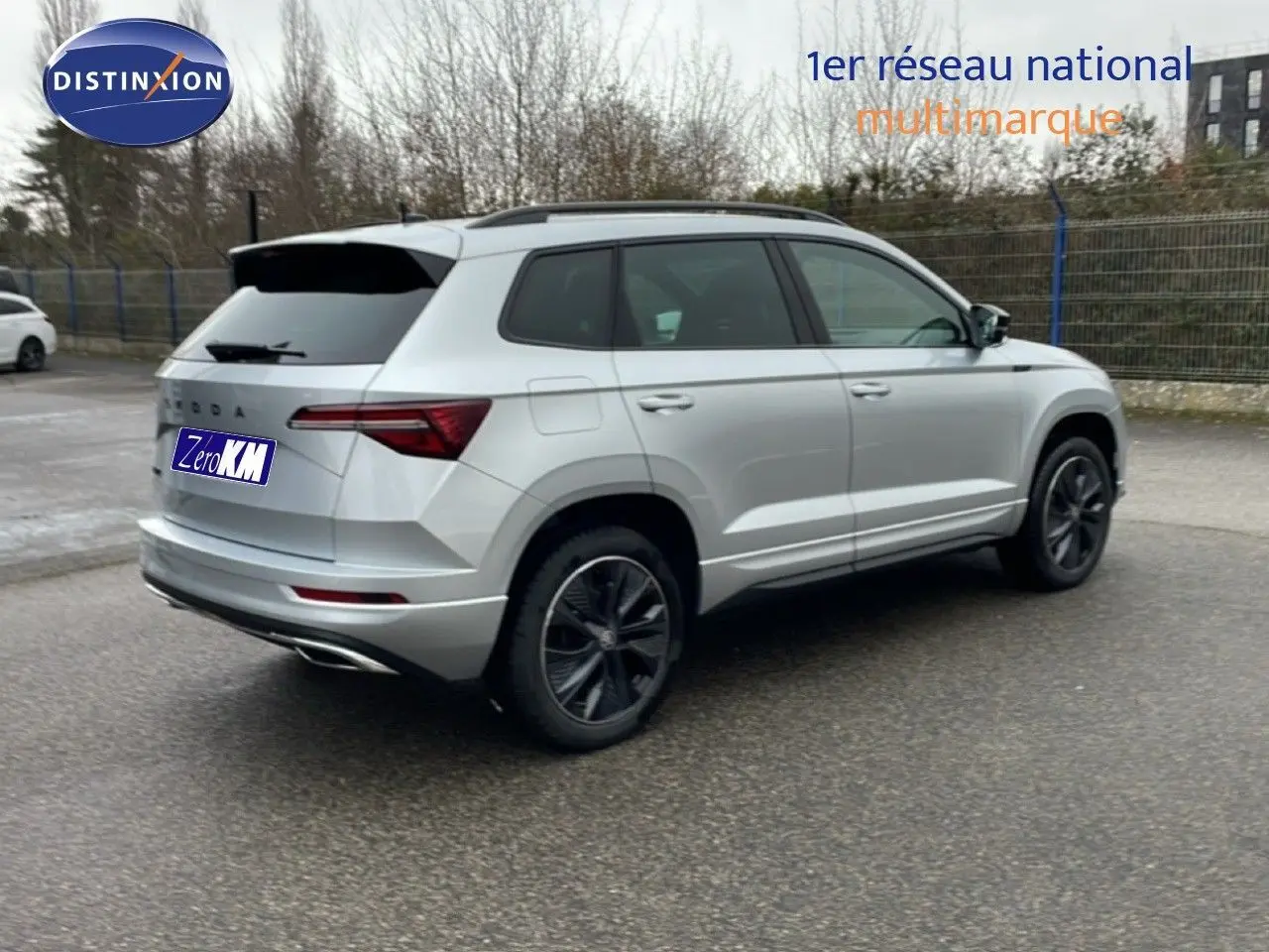 Vue 3/4 arrière droite d'un Skoda Karoq gris argent métallisé avec jantes noires et toit ouvrant panoramique.