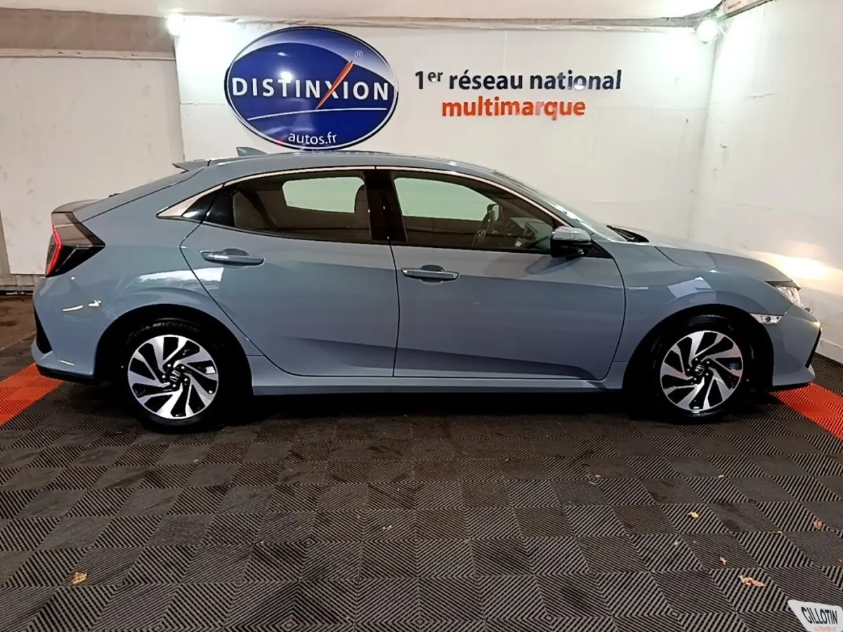 Vue latérale droite d'une Honda Civic 1.0 i-VTEC Exclusive gris foncé, avec jantes alliage et feux arrière distinctifs.