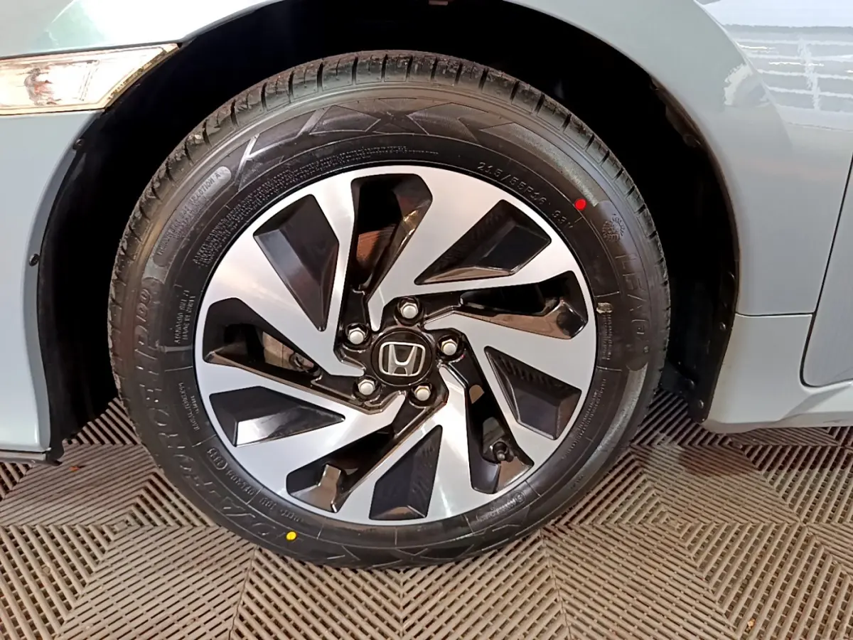 Gros plan sur la roue avant droite de la Honda Civic gris foncé, mettant en valeur la jante alliage au design moderne.