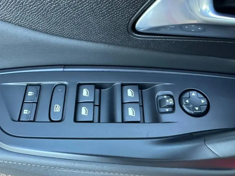 Vue rapprochée des commandes de lève-vitres et rétroviseurs sur la porte côté gauche d'une Peugeot 308 SW 2024.