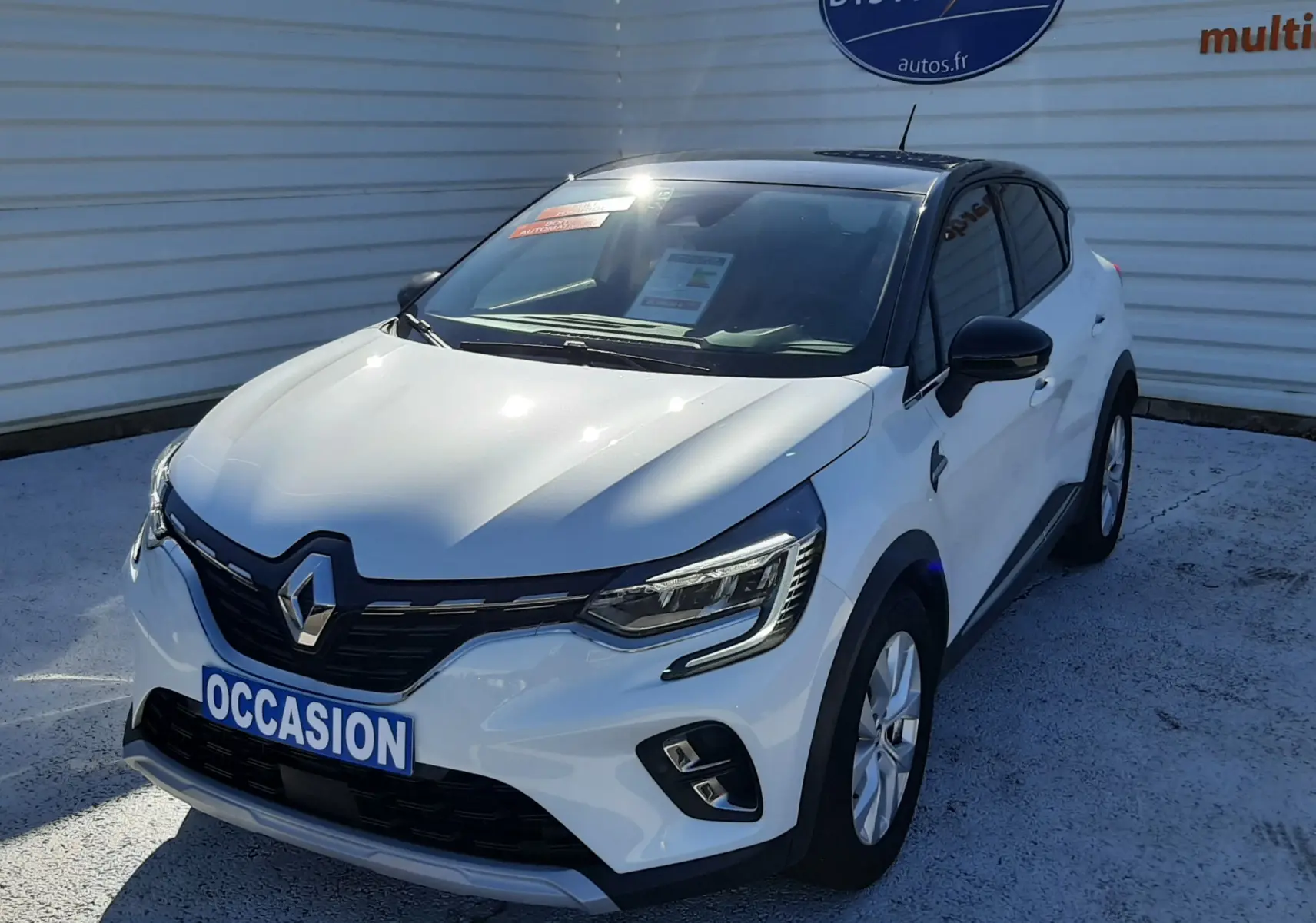 Renault Captur E-Tech blanc nacré avec toit noir, vue 3/4 avant droit, calandre noire et phares LED allumés.