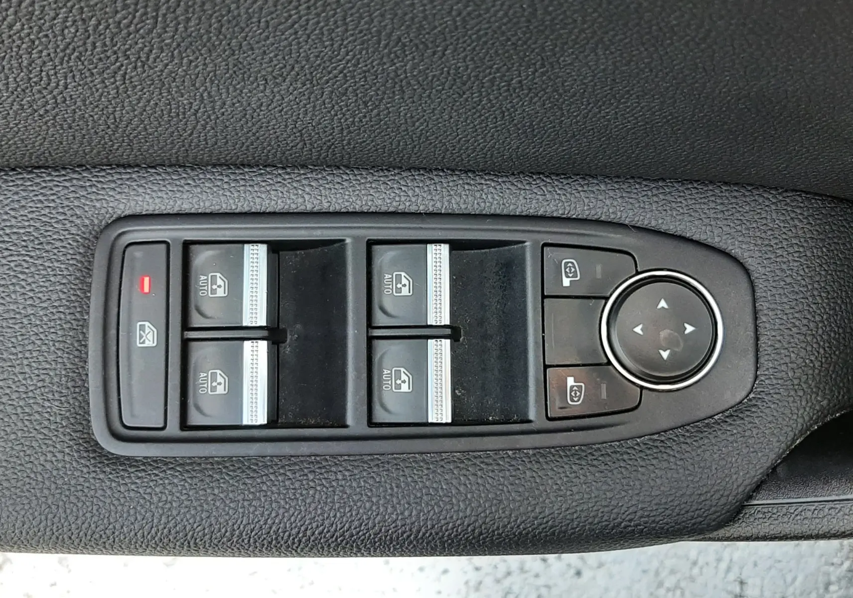 Panneau de commandes des vitres électriques et rétroviseurs sur la portière côté gauche d’un Renault Captur blanc nacré.