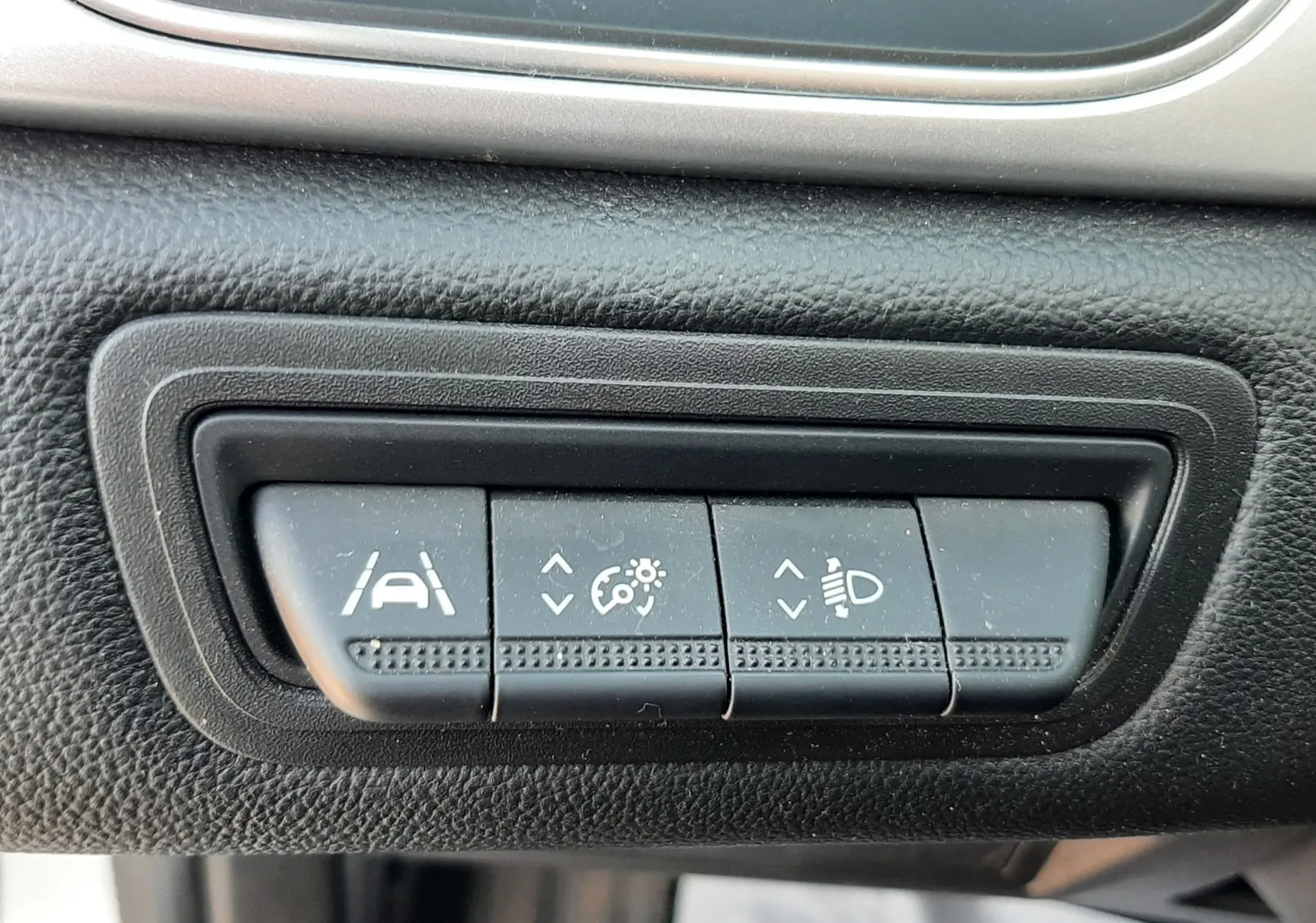 Gros plan sur les boutons de réglage d'assistance à la conduite et des phares dans l'habitacle noir du Renault Captur E-Tech 2022.