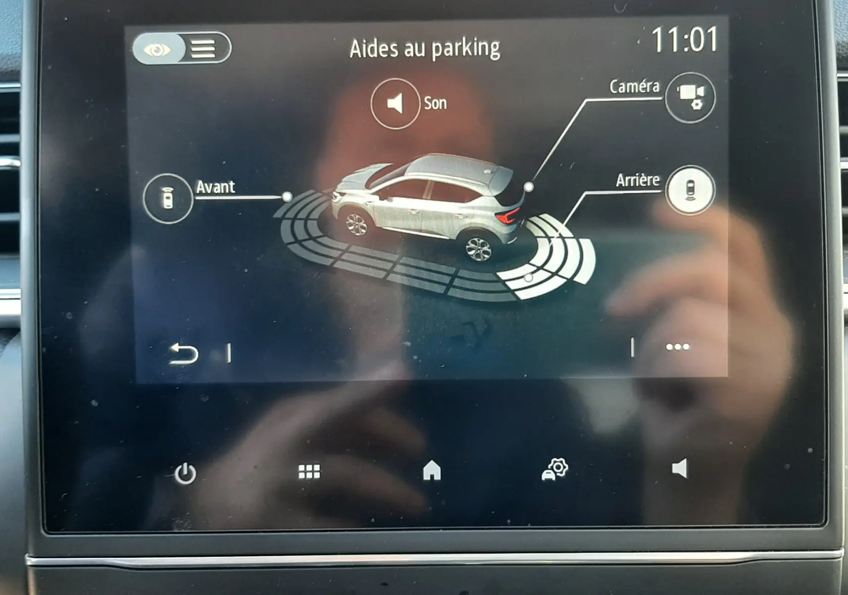 Écran tactile intérieur montrant l'aide au parking du Renault Captur blanc nacré avec toit noir, vue 3D du véhicule.