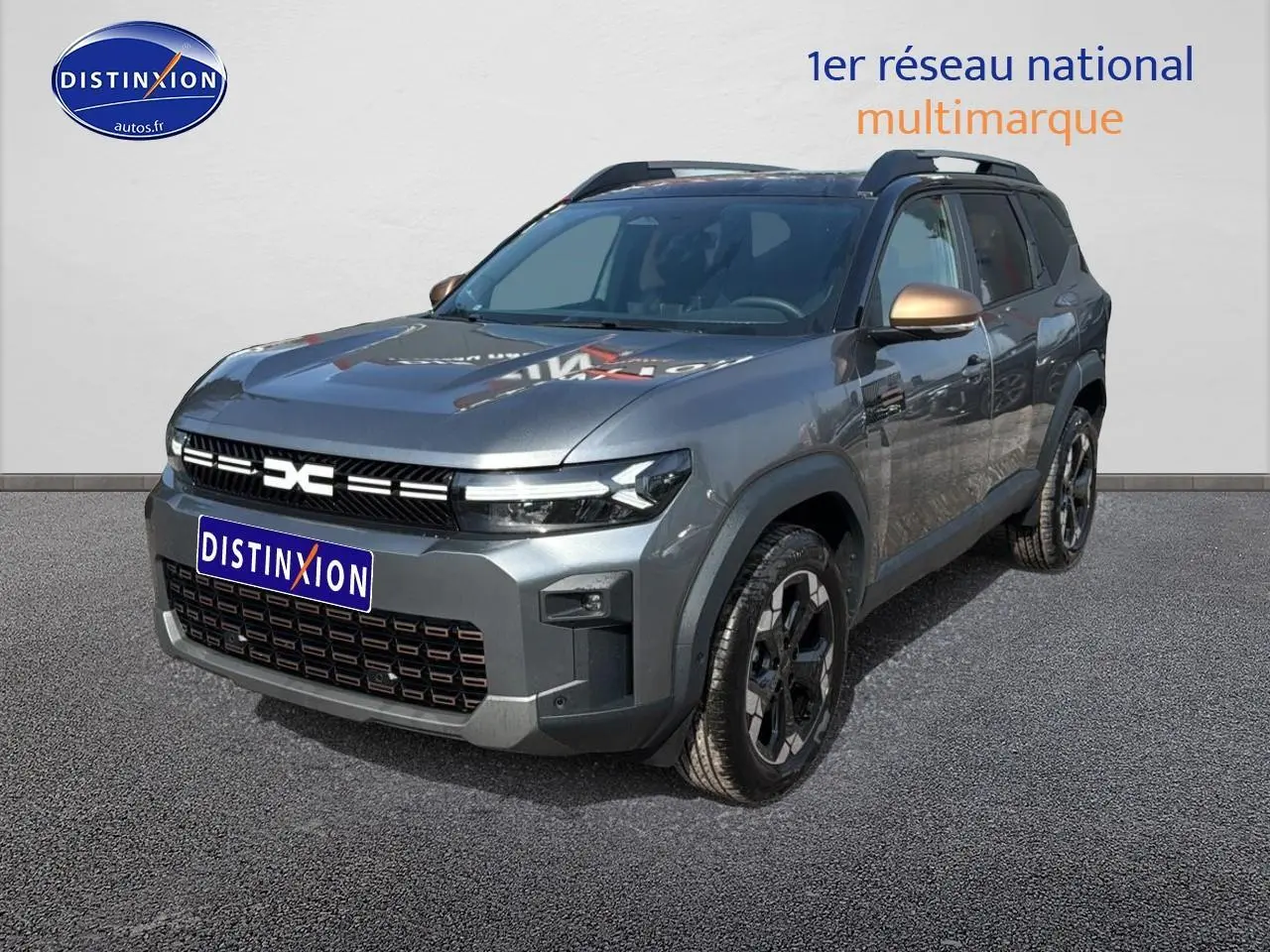 Vue 3/4 avant d’un Dacia Bigster gris schiste avec rétroviseurs bronze et jantes noires sur fond neutre.