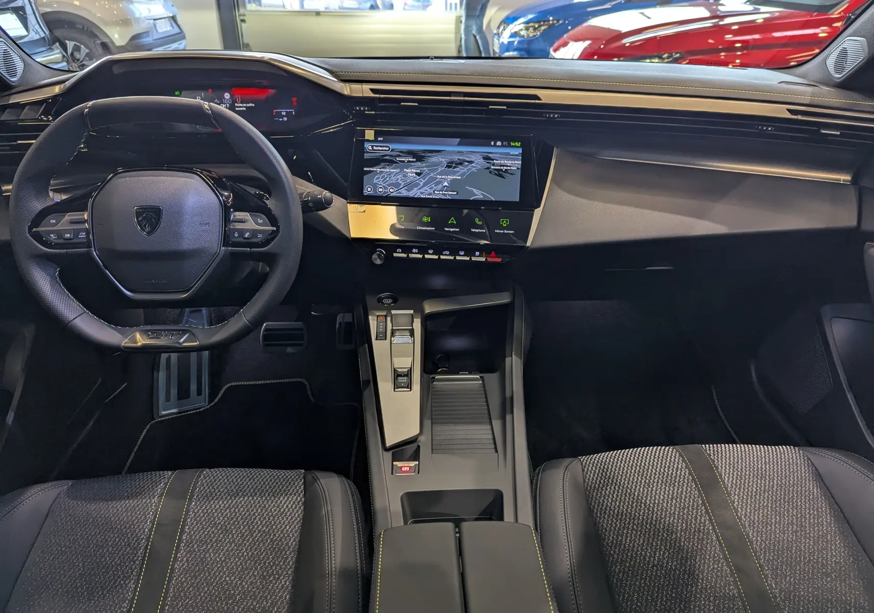 Vue intérieure avant de la Peugeot 308 GT 2025 avec tableau de bord numérique et console centrale moderne noire.