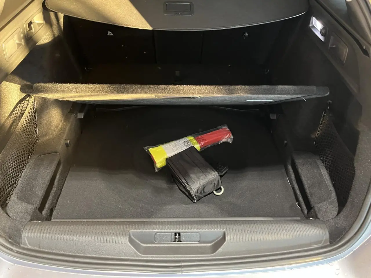 Coffre ouvert d'un Peugeot 308 SW gris clair Metal Artense, montrant le compartiment de rangement avec un triangle de signalisation.