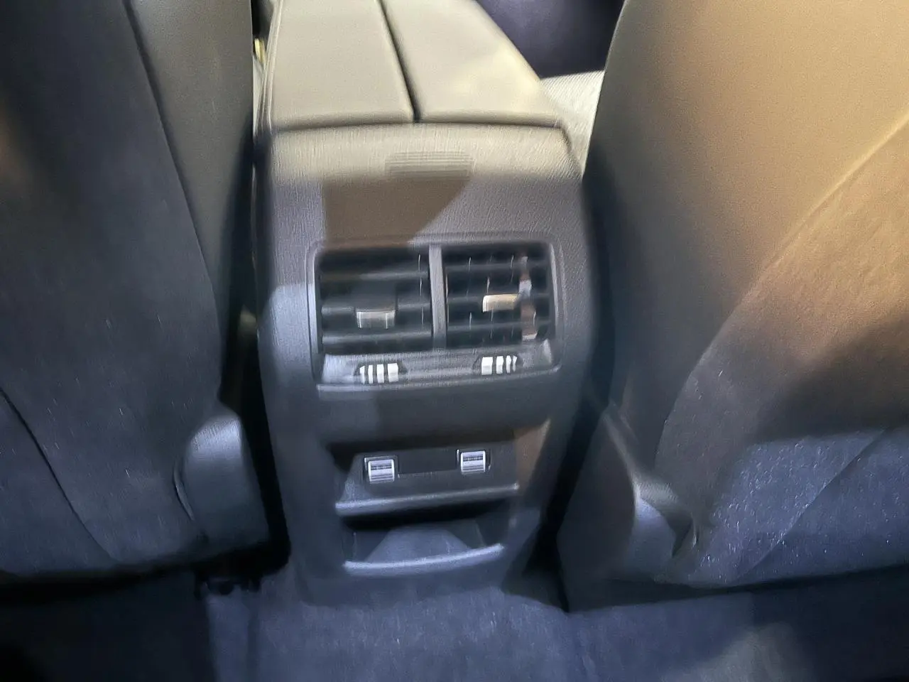 Vue rapprochée des aérateurs arrière et ports USB entre les sièges avant d'une Peugeot 308 SW gris clair 2024.